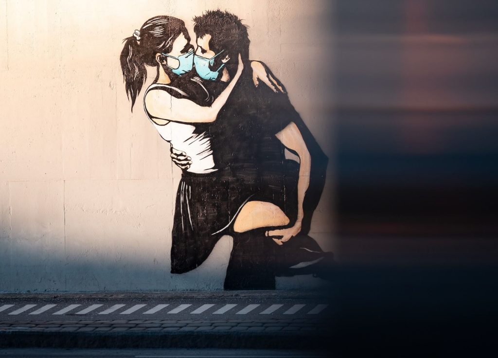A graffiti of a couple kissing with masks